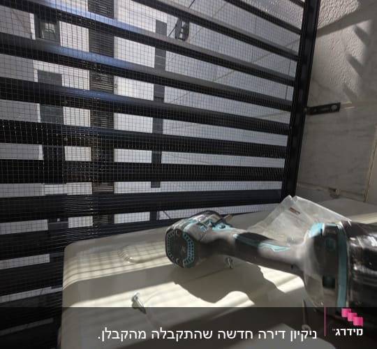 מברגה וברגים על משטח ליד סורגי מתכת